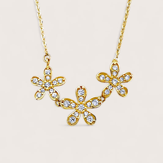 close up of Gold necklace with floral pendants on a light beige background