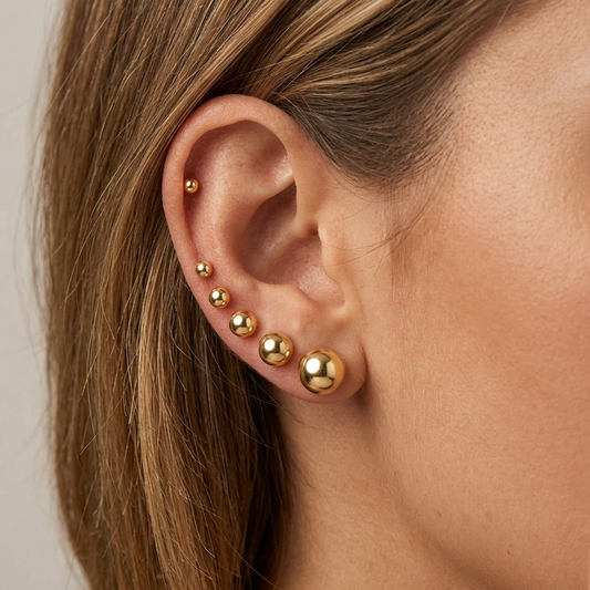 A styled ear stack showcasing the dainty 2mm -8mm gold-filled ball studs worn together in secondary and helix piercings on a model.s