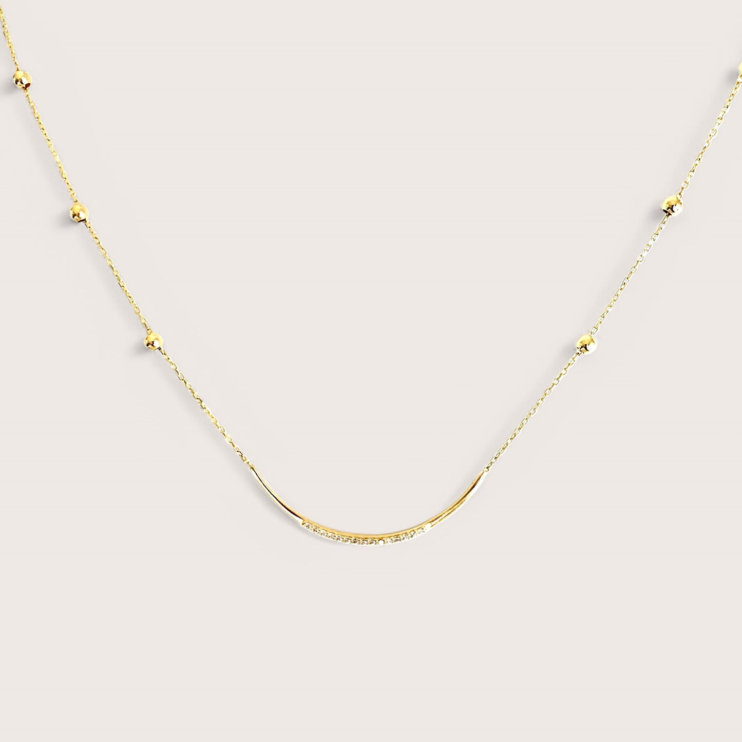 A 14K gold U-bar pendant necklace with delicate twinkling CZ stones adorned across a gold bar