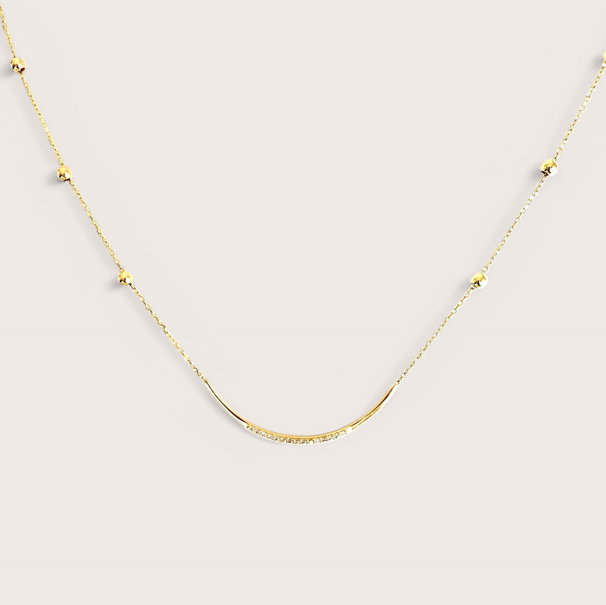 A 14K gold U-bar pendant necklace with delicate twinkling CZ stones adorned across a gold bar