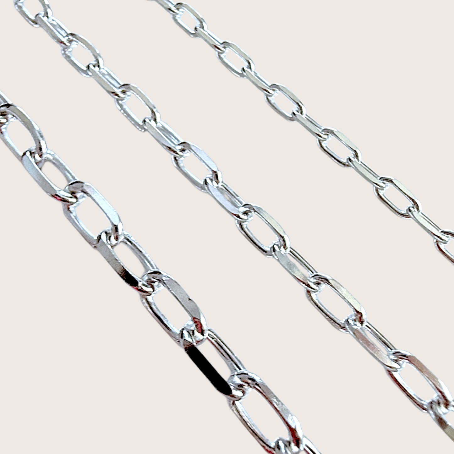 Close-up of a silver chain on a light beige background