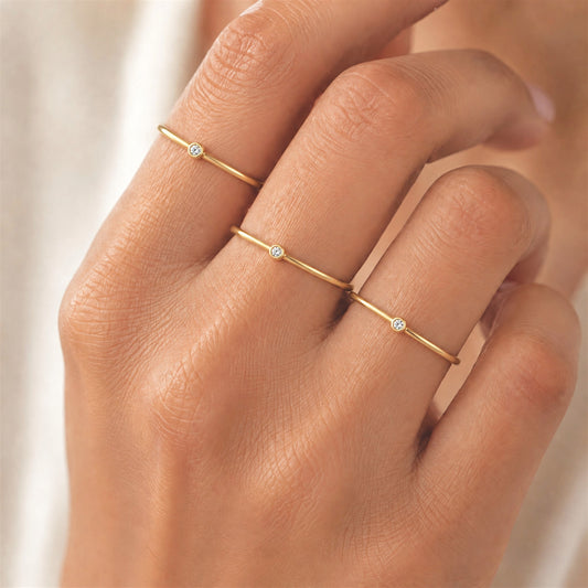 Model wearing gold filled rings on index, middle and ring fingers featuring the 2.0mm lab diamond bezel solitaire
