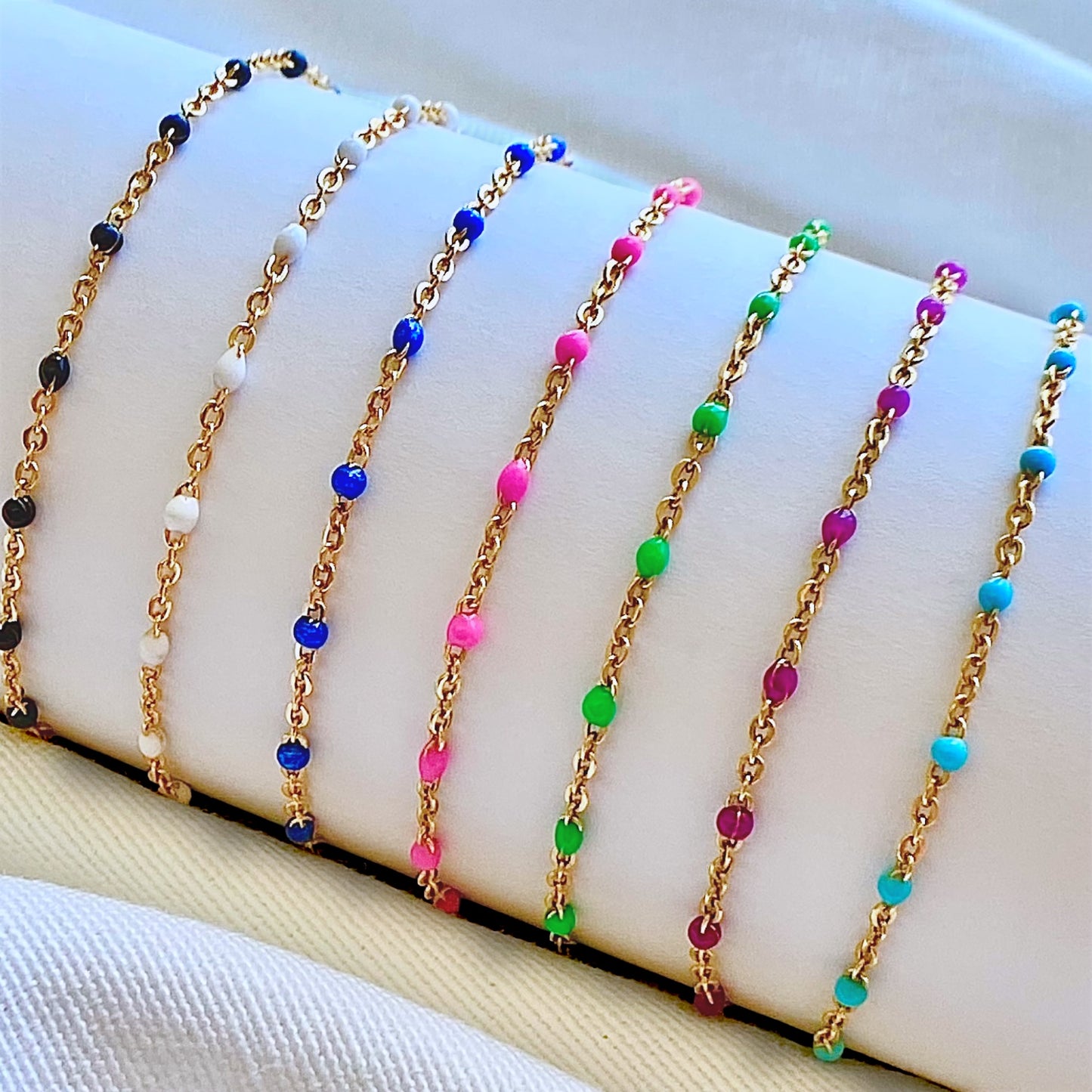 Close up macro shot highlighting the vibrant pink resin enamel beads spaced along the dainty 14K gold filled satellite chain