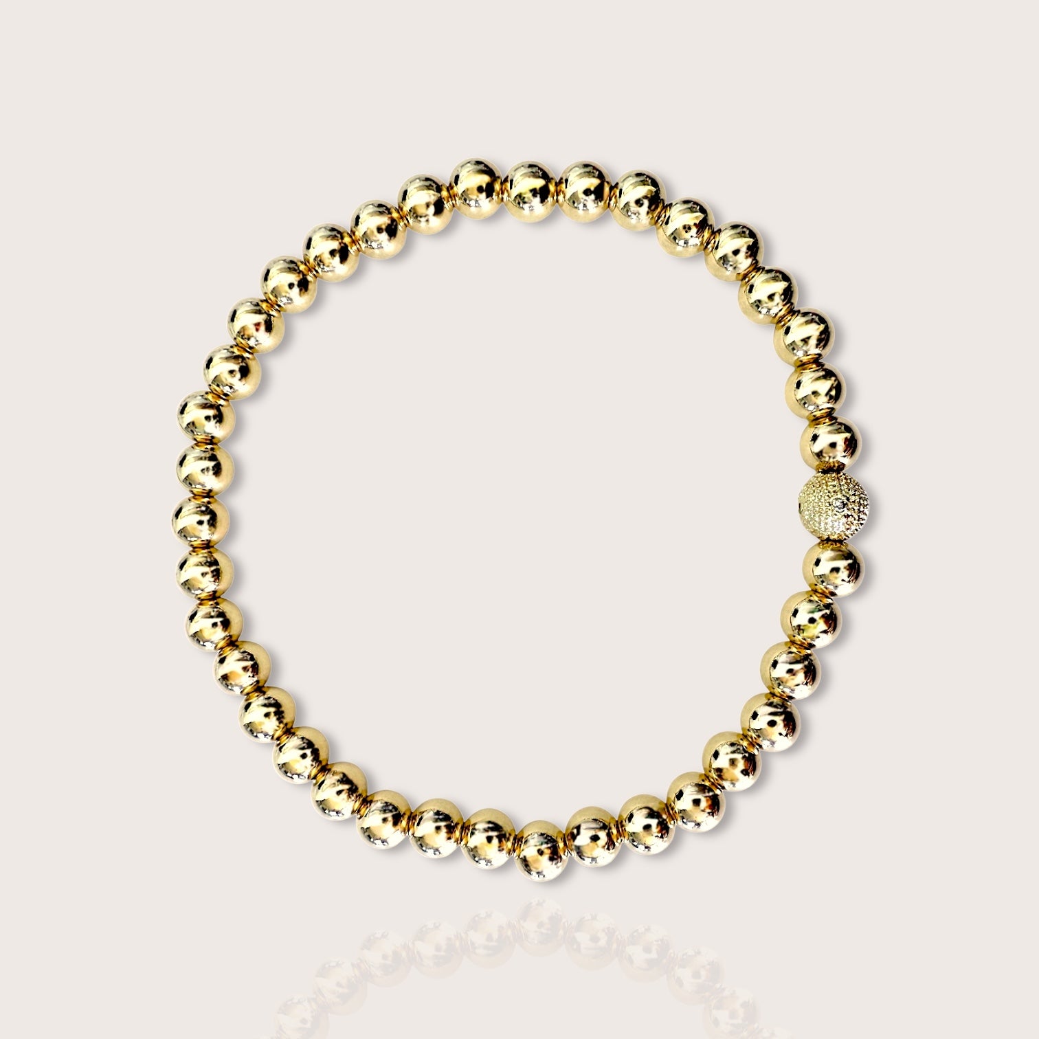 A bracelet featuring yellow gold beads with one diamond-accented bead, displayed against a white background.