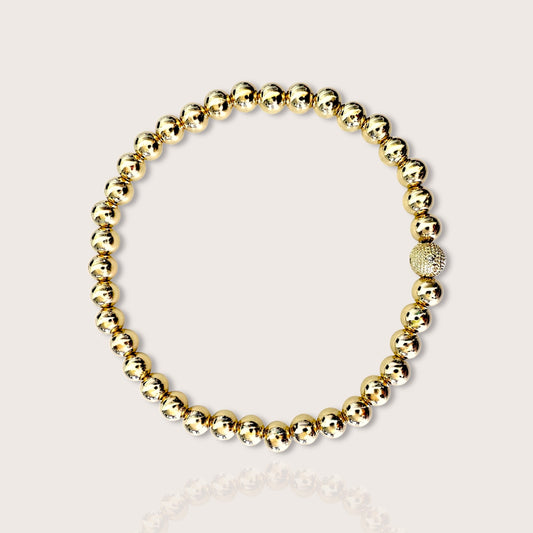 A bracelet featuring yellow gold beads with one diamond-accented bead, displayed against a white background.