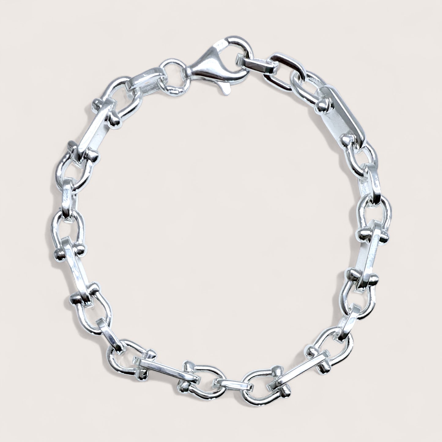 Silver u-link chain bracelet on a light beige background