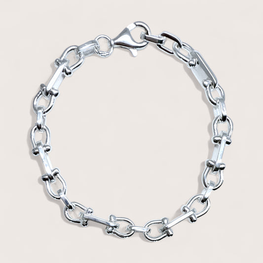 Silver horse shoe u-link chain bracelet on a light beige background