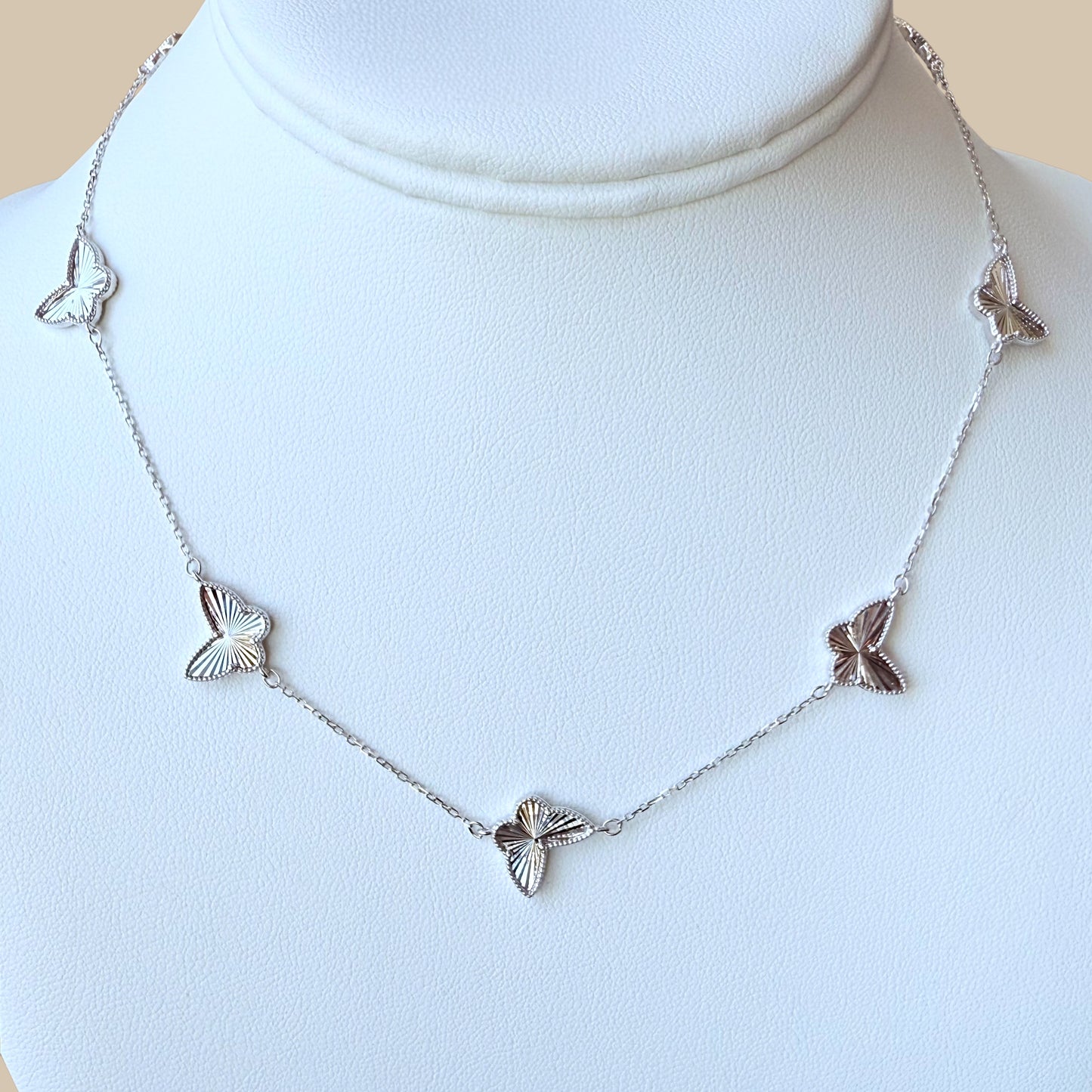 Close-up of faceted butterfly charm on high-polish silver chain