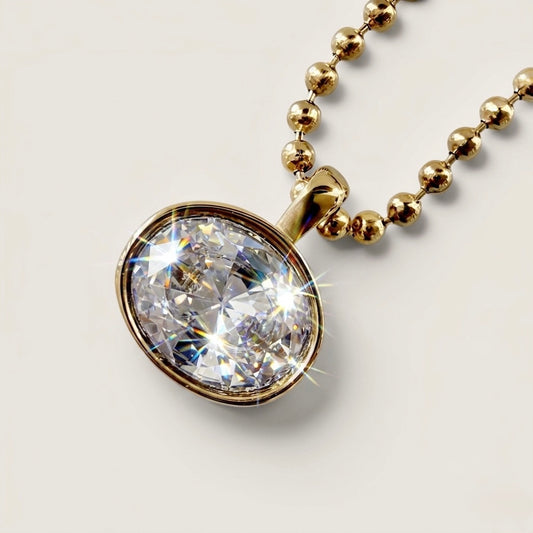 Close-up of the horizontal oval-cut cubic zirconia stone in a polished 18K gold bezel setting, showing light reflection on the beaded chain.