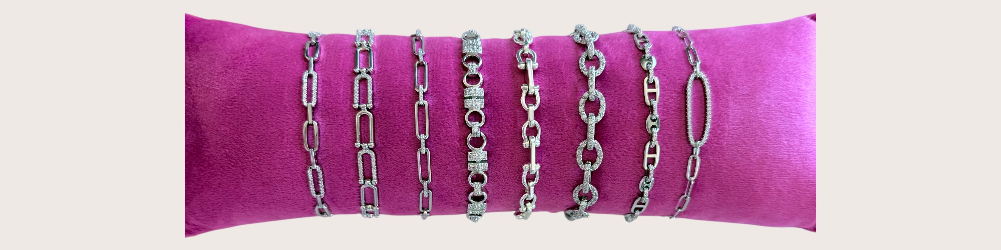 Set of silver chains on a pink cushion against a light gray background