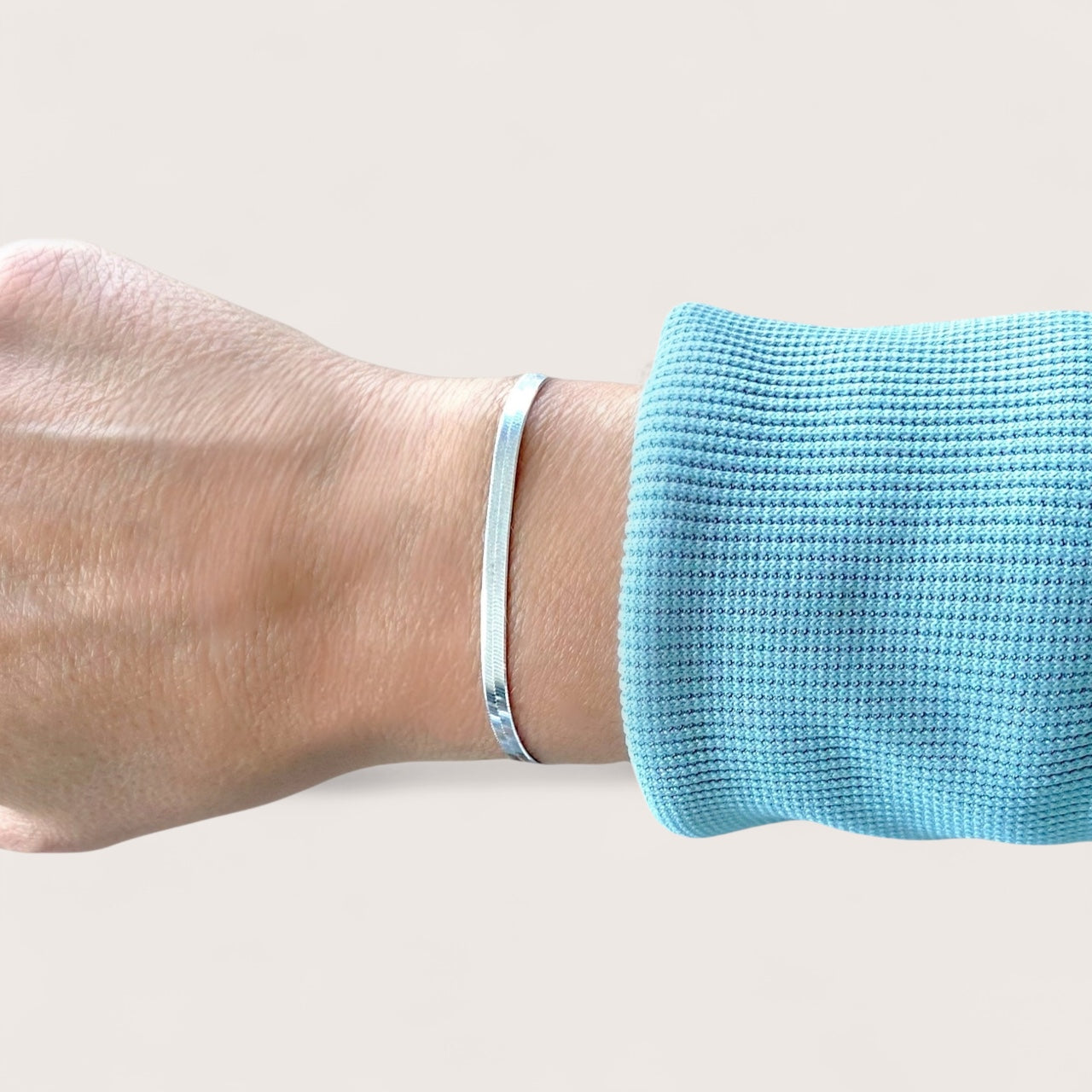 925 Sterling Silver Herringbone Bracelet on a wrist with a light blue textured sleeve against a neutral background
