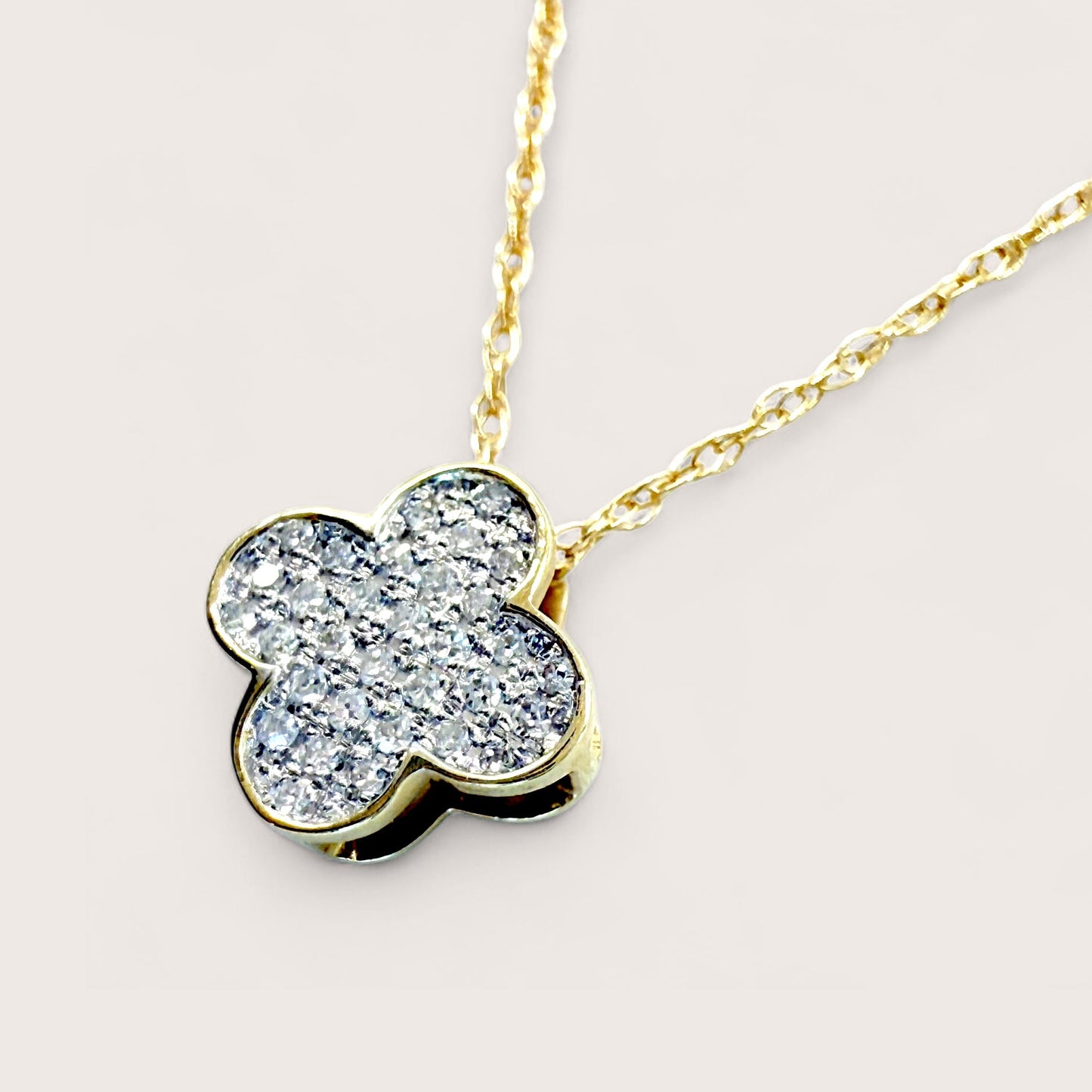 Close up of 14K Yellow Gold Necklace with a dainty Diamond clover-shaped pendant on a delicate open rope chain