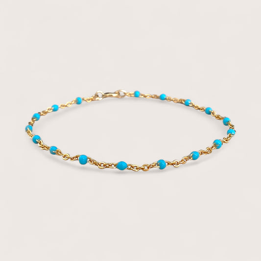 This high-quality Vibrant Turquoise Gold Chain Bracelet is made with 1.8mm delicate enamel beads and strong 14K gold fill. It's perfect for everyday wear, and can even be worn in the shower without losing its shine or color. This one-of-a-kind bracelet is handmade in sunny Laguna Beach, CA and comes in customizable sizes for everyone from newborns to adults. It's a fun and functional gift suitable for any occasion!