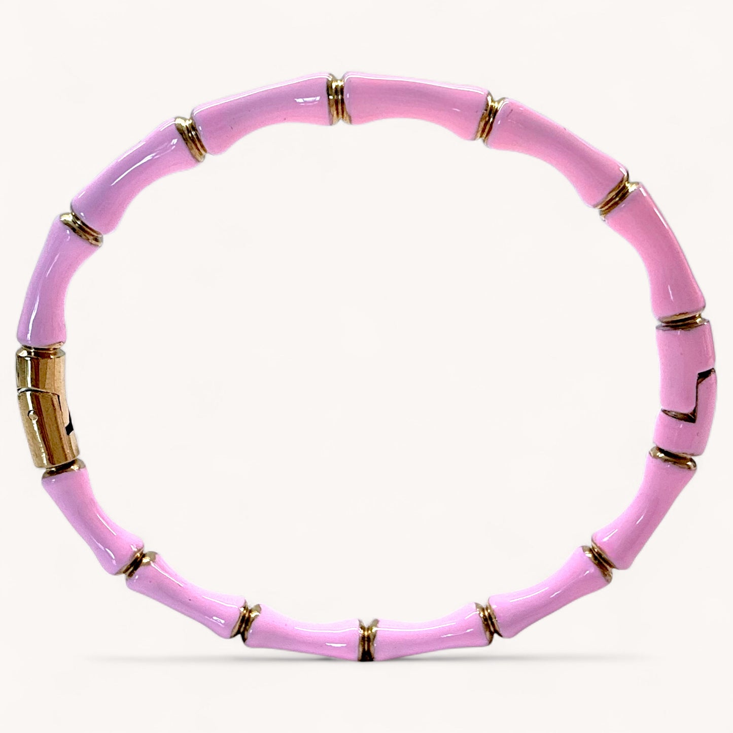 Pink beaded bracelet with gold accents on a white background