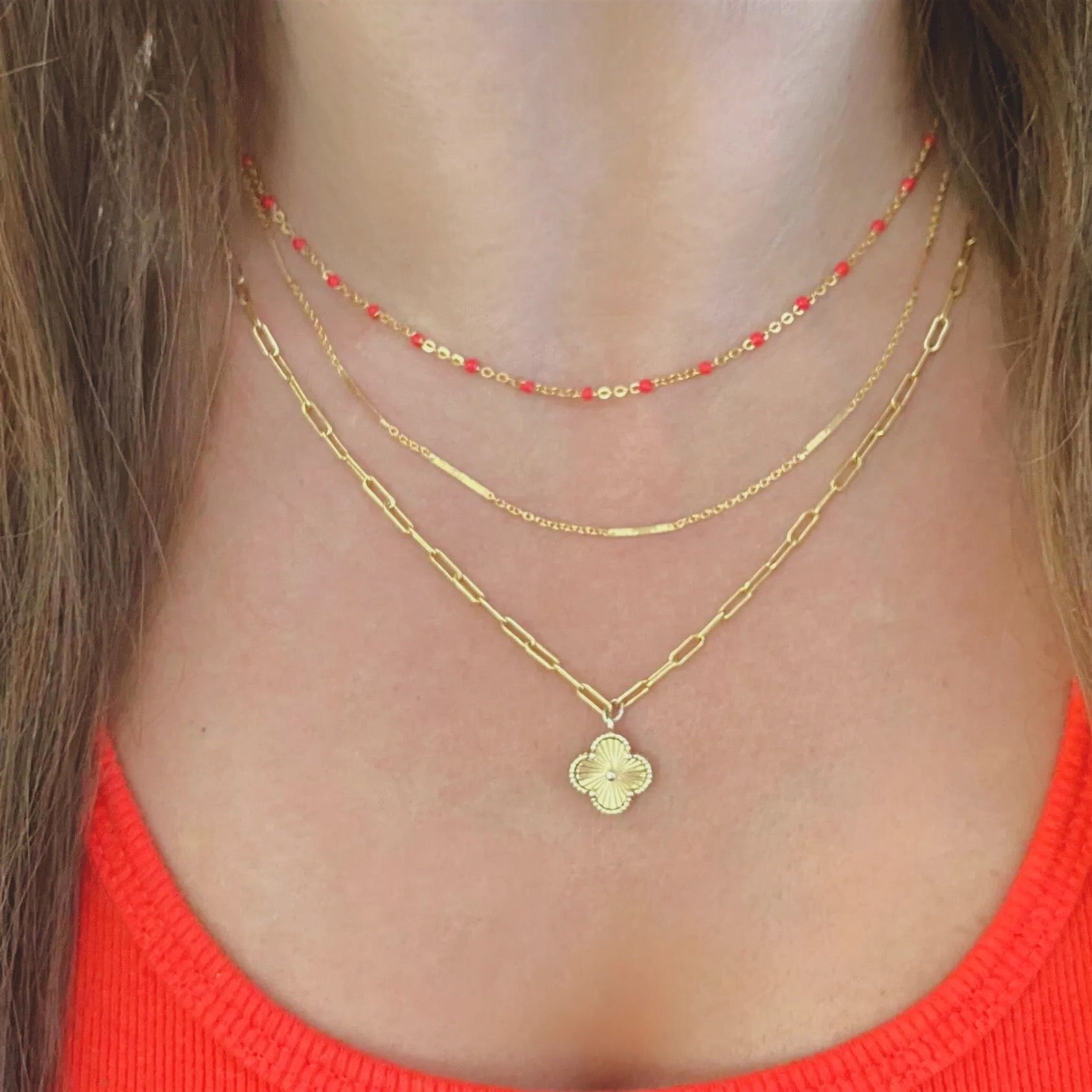 Close-up of a person wearing gold necklaces with a red top