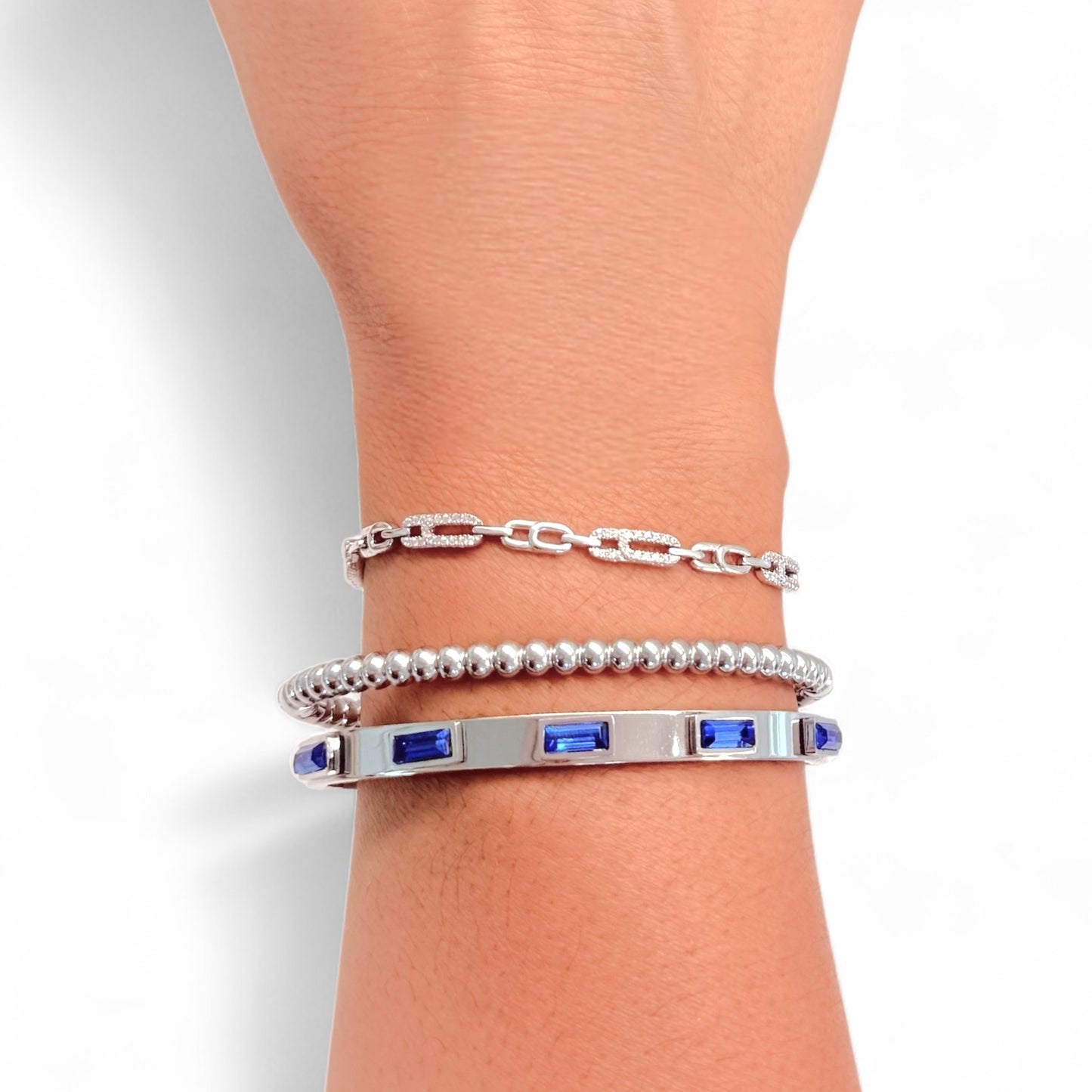 Silver bracelet with blue stones on a wrist against a light background