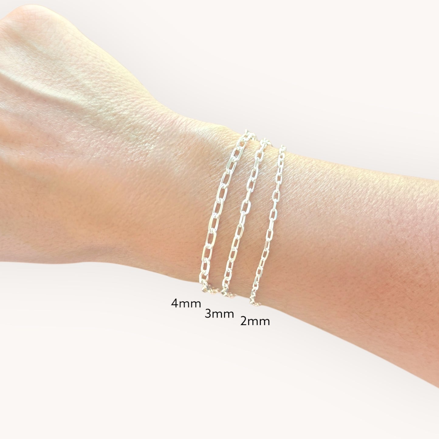 Silver chain bracelets on a wrist with size labels