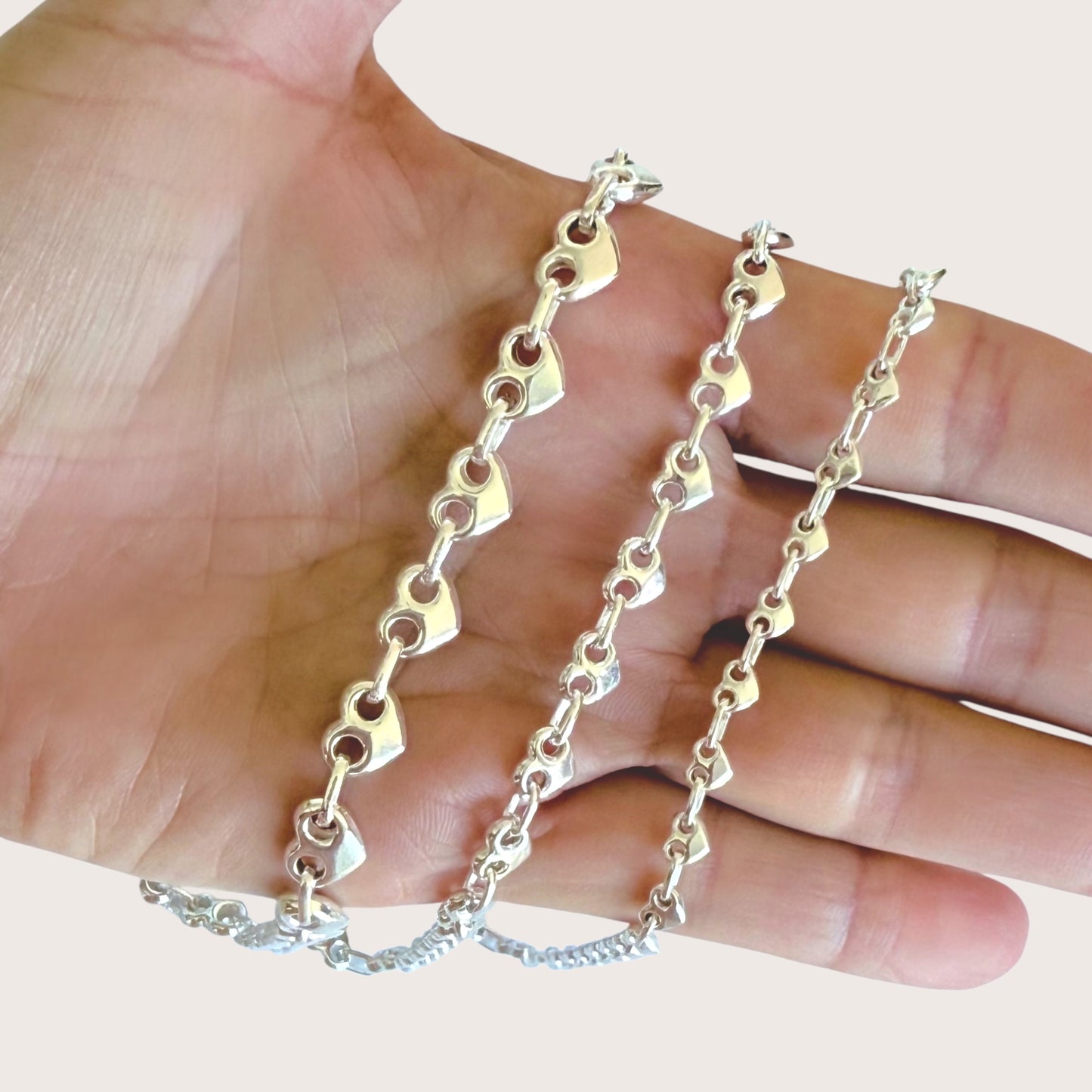 Silver chain held in a hand against a light background