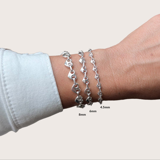 Heart-shaped puffed mariner chain bracelet in 925 sterling silver shown on a model's wrist, custom-fitted, bold and polished finish