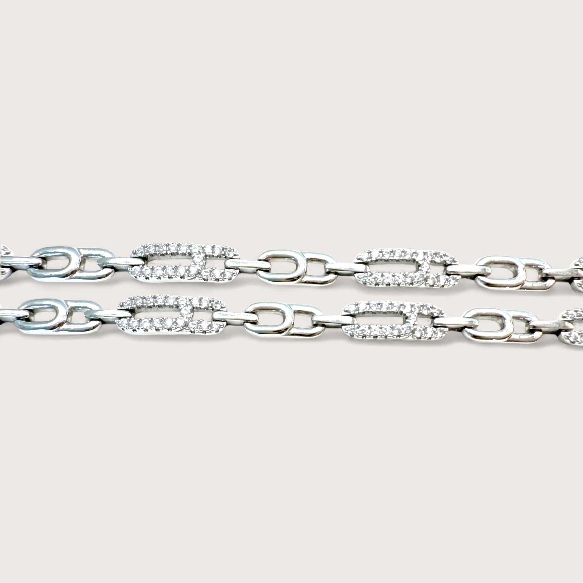 Silver chain bracelet with clear gemstones on a light gray background