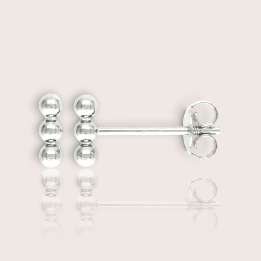 Close up of triple bead vertical bar stud earrings available in solid sterling silver. Waterproof, tarnish-free, and hypoallergenic.