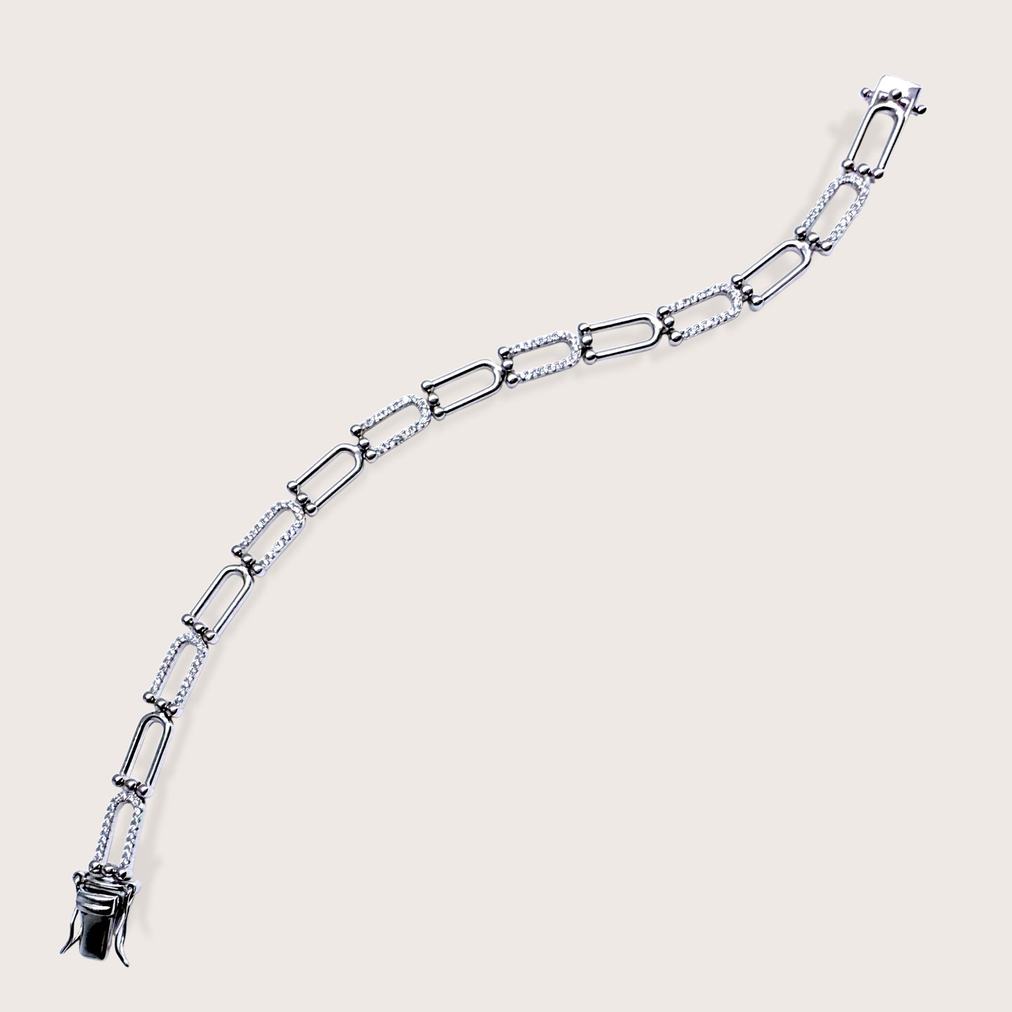 Image of entire bracelet including claps Silver chain bracelet on a light beige background