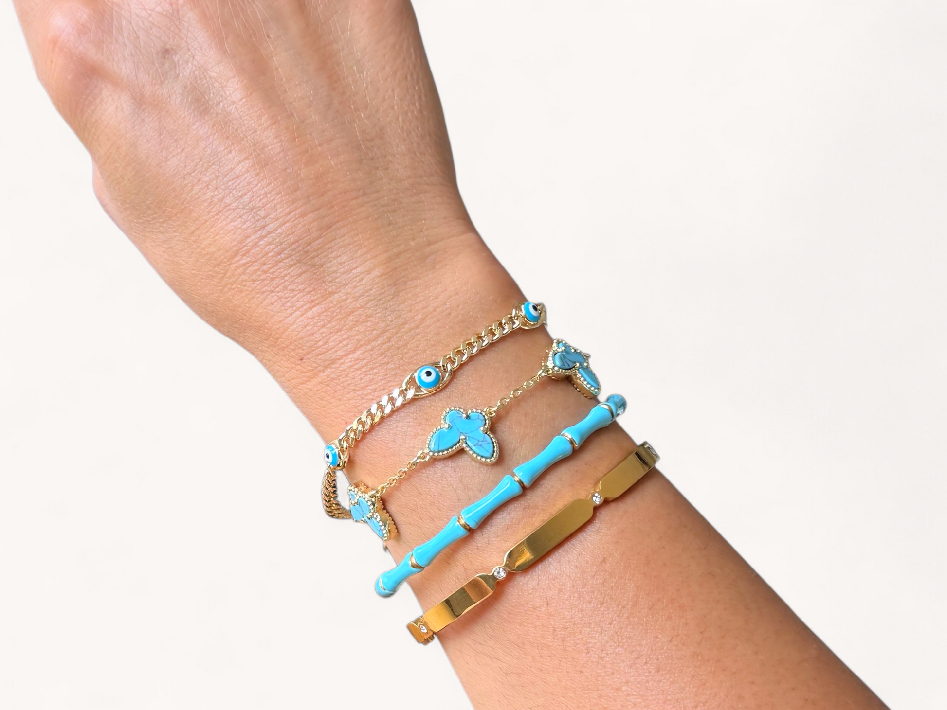Hand wearing multiple bracelets stacked with blue and gold colors on a white background
