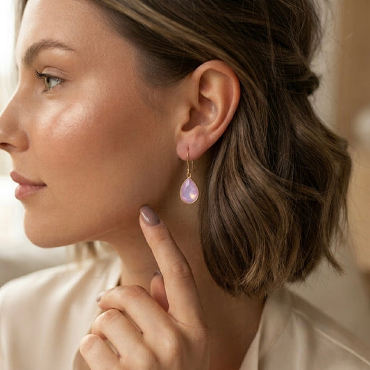 Side profile of a model wearing pink opalescent teardrop crystal dangle earrings layered in a curated ear stack by Ashley Nicole Jewelry