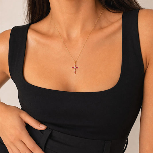 Petite ruby and diamond cross necklace worn with a black square-neck top, showing the chain drape