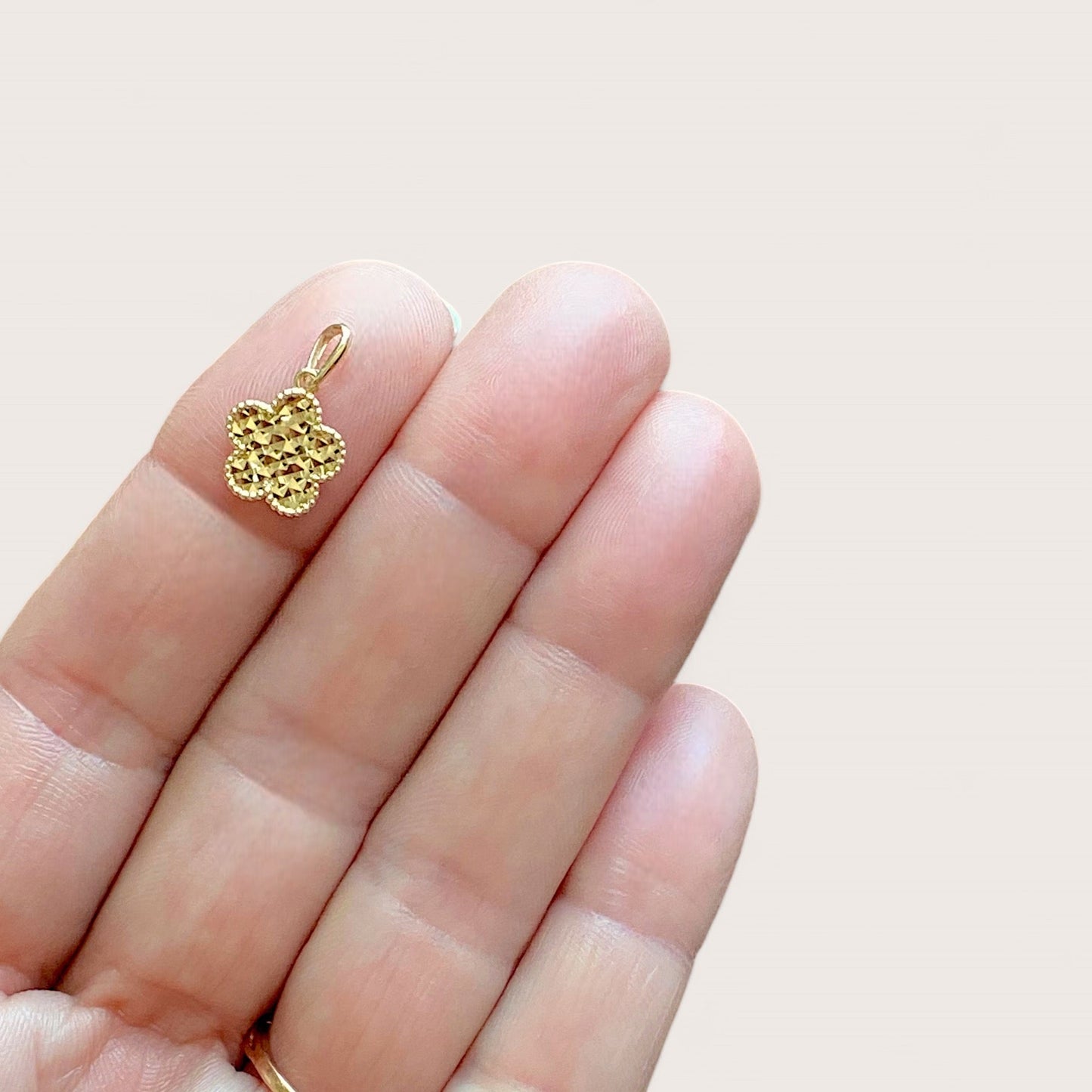 10mm Gold Clover Flower Charm shown in hand