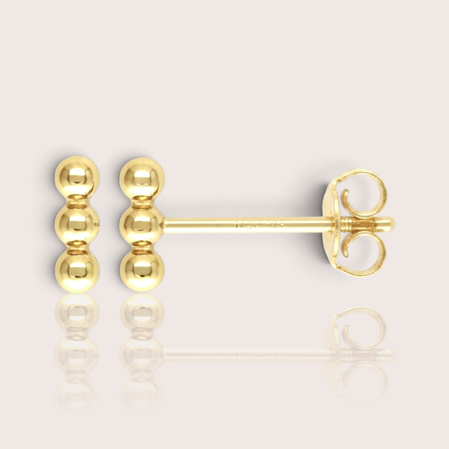 Close-up profile 14K gold-filled triple bead vertical bar stud earrings, display the minimalist, delicate gold cluster stud. The background is a soft, minimalist studio setting