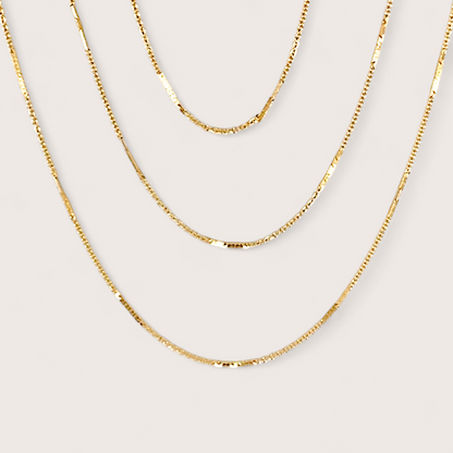 14K Gold Filled Bar Station Chain Necklace on plain background showing dainty dapped bar links layered with other gold chains.