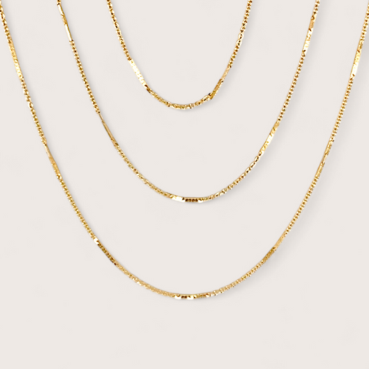 14K Gold Filled Bar Station Chain Necklace on plain background showing dainty dapped bar links layered with other gold chains.