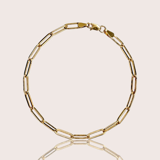 Solid 14K yellow gold paperclip link bracelet on a light beige background