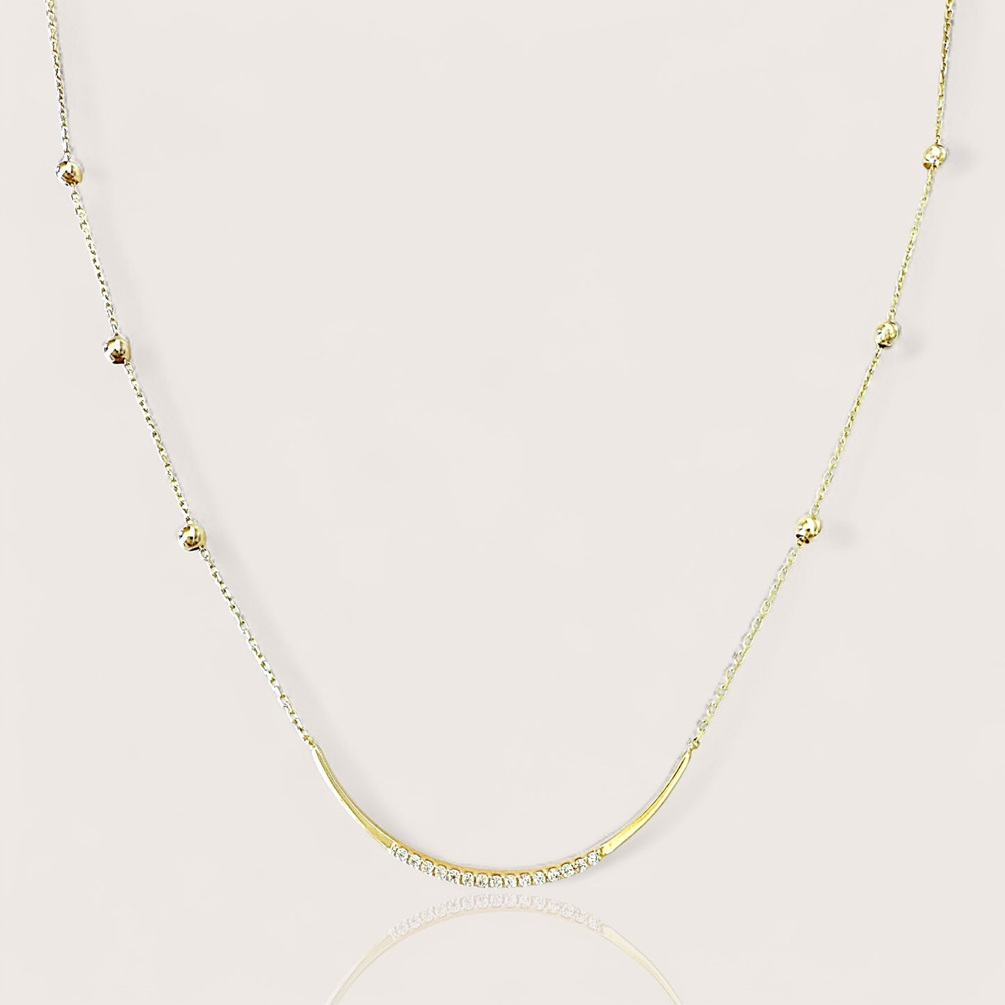 Gold necklace with a u bar pendant adorned with cz gemstones and small beads