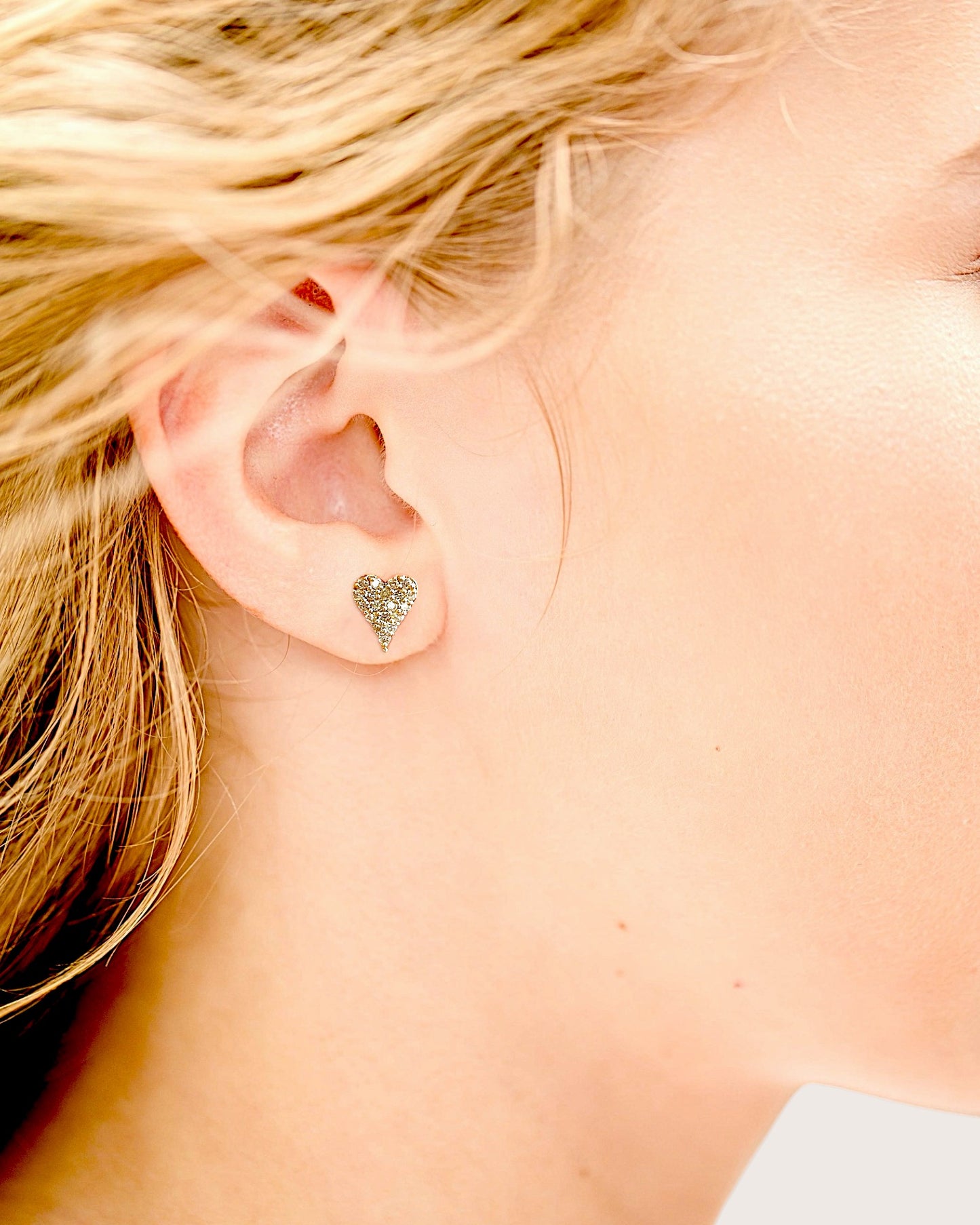 14K yellow gold pave diamond heart stud earrings on a model 