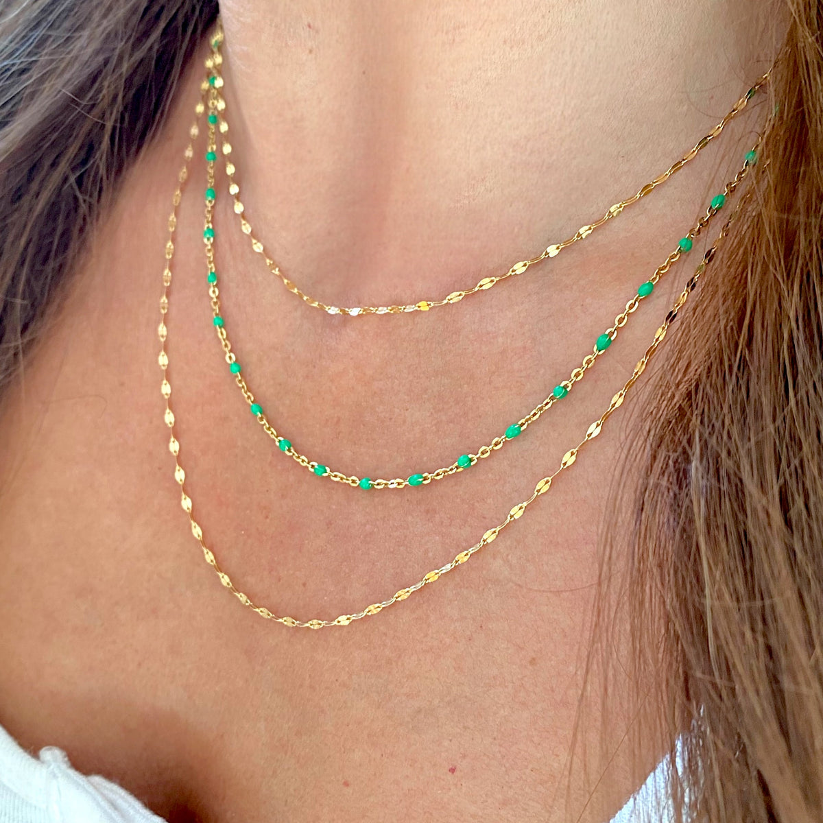 Gold-filled mirror Valentino necklaces layered with a green station necklace