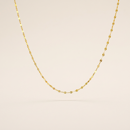 Single gold-filled mirror Valentino chain necklace arranged in a U shape on an ivory background