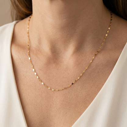 Single gold-filled mirror Valentino chain necklace worn above an ivory blouse