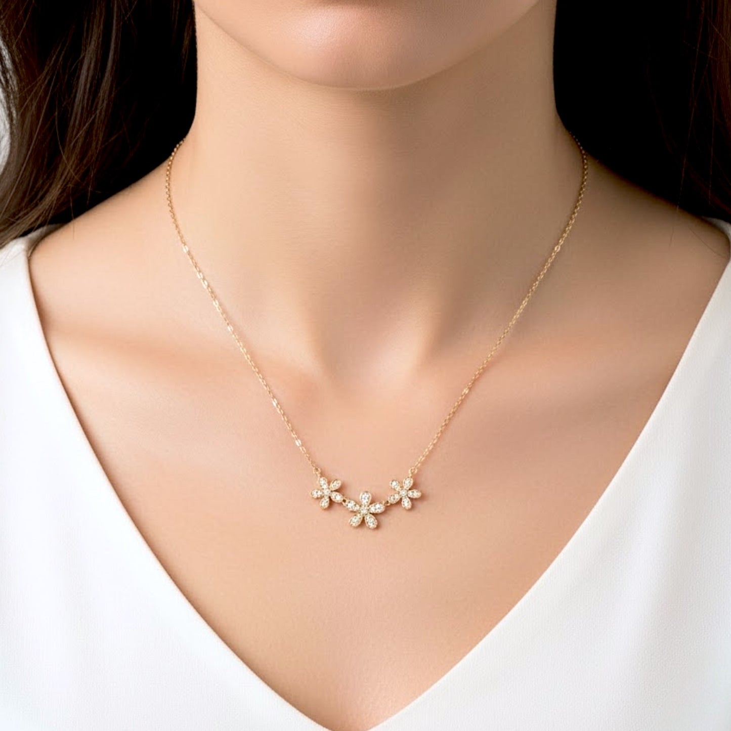 Close-up photograph of the 14k gold-filled Three Flower Bar Necklace by Ashley Nicole Jewelry. The three-flower CZ-set pendant is centered on the model's neckline, drapes at an 18-inch length, highlighting the substantial 5mm x 9.5mm link scale.
