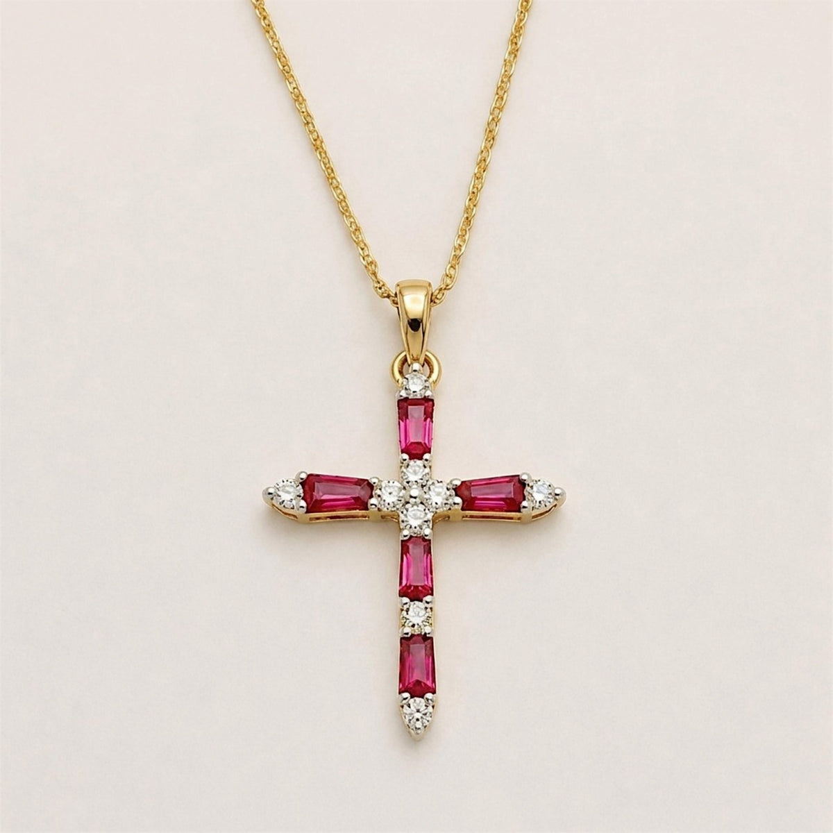 Front view of a yellow gold cross pendant with five rectangular rubies and round diamond accents