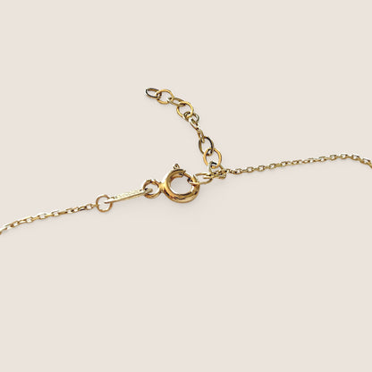 Close-up of the gold necklace’s spring-ring clasp, flat end tab, and oval-link extension chain