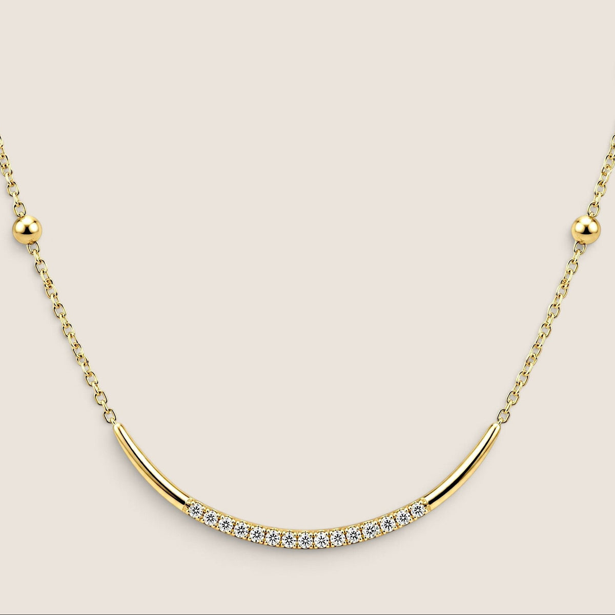 Close-up of the curved gold U-bar with a central row of cubic zirconia and round gold beads along the chain