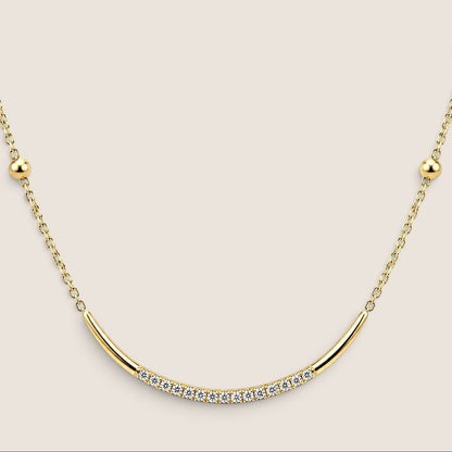 Close-up of the curved gold U-bar with a central row of cubic zirconia and round gold beads along the chain