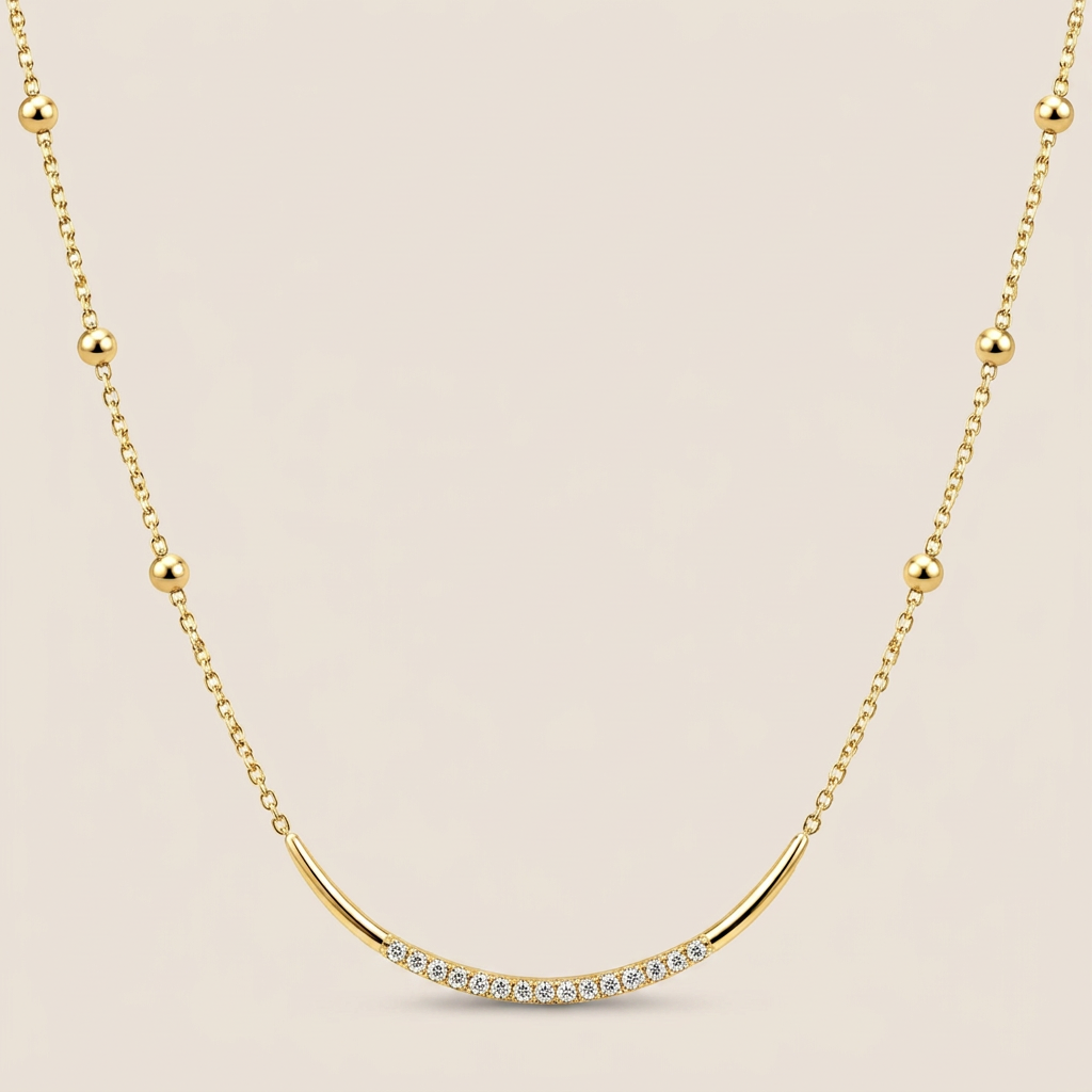 Yellow gold satellite necklace with round bead stations and a curved CZ-accented U-bar on a warm beige background