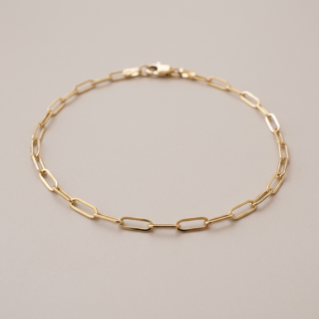 Angled view of a gold paperclip bracelet showing the polished flat link surfaces, with the clasp toward the back