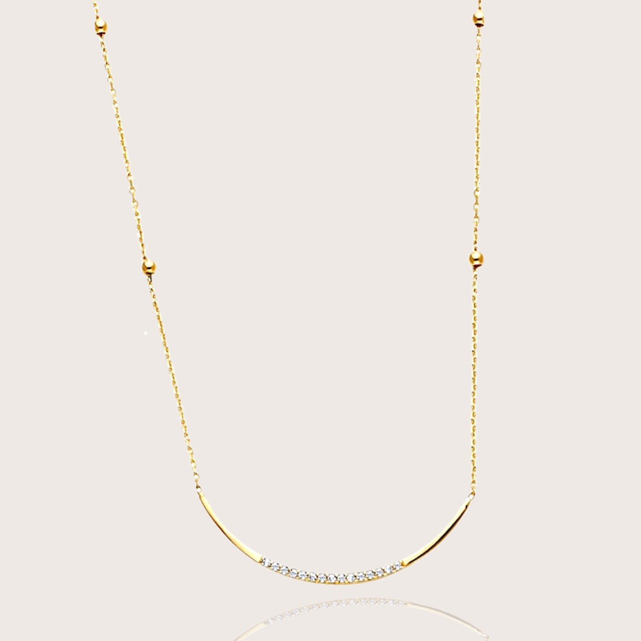 Gold necklace with small diamonds on a light gray background