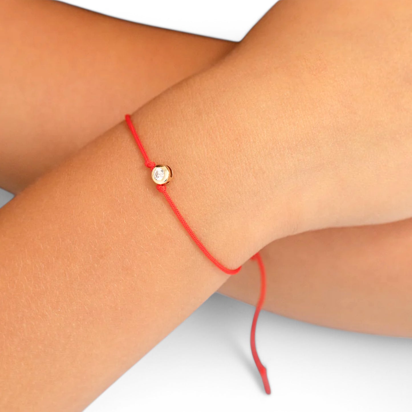 14K yellow gold bezel-set cubic zirconia charm on an adjustable red string cord worn on a petite wrist⁠