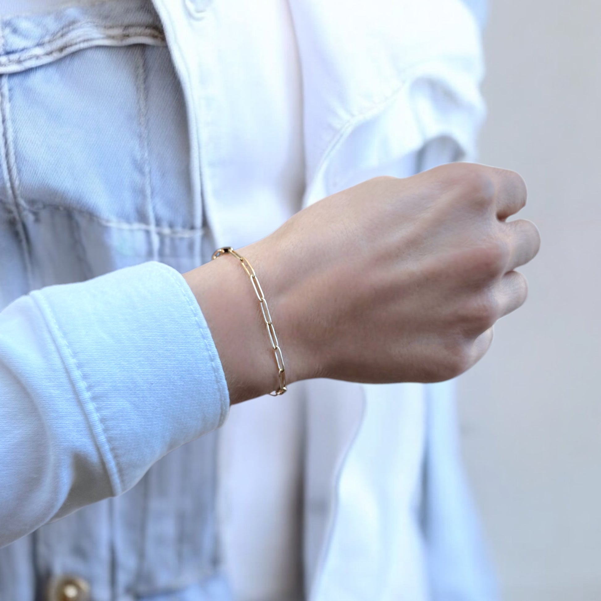 14k gold paperclip chain bracelet on a a persons wrist