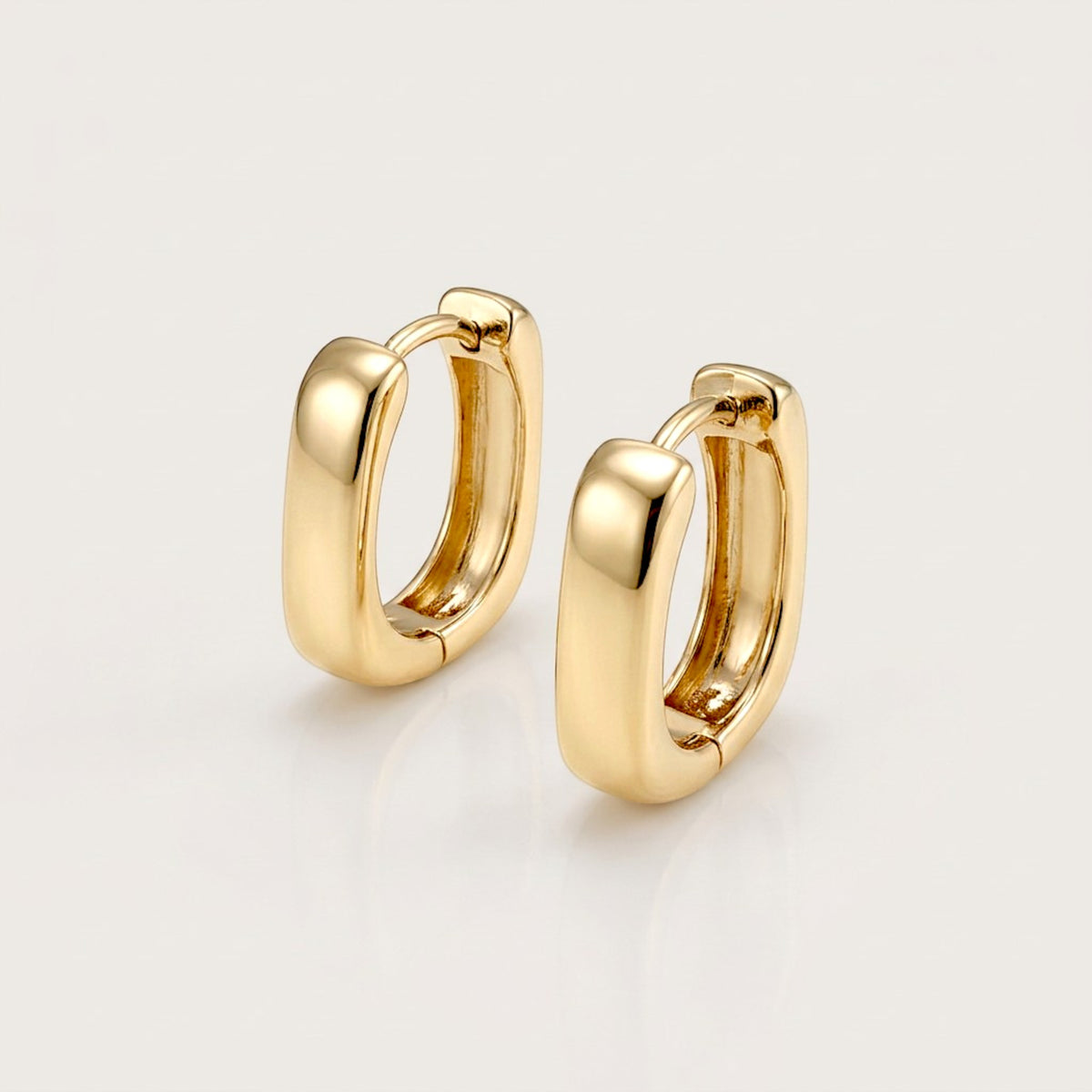 Pair of chunky gold rectangular huggie earrings with rounded corners, shown at an angle on a neutral background.